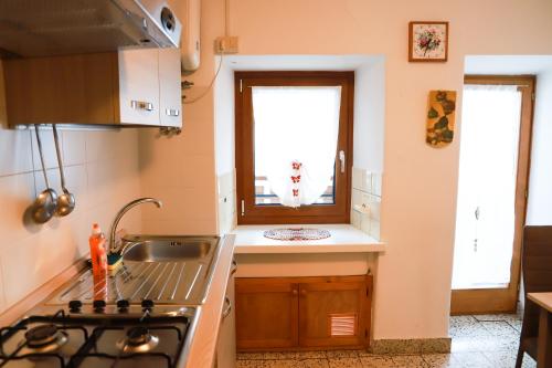 a kitchen with a stove and a sink and a window at COL DE RIF Appartamento Storico nelle Dolomiti in Falcade