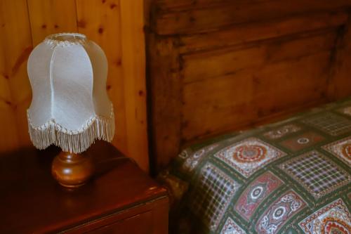 a lamp sitting on a table next to a bed at COL DE RIF Piccolo Appartamento Storico Dolomiti in Falcade