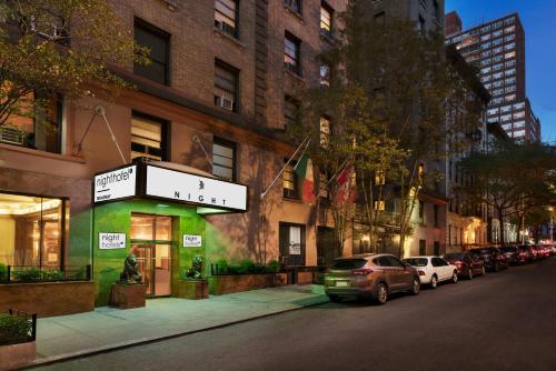 una strada con auto parcheggiate di fronte a un edificio di Night Hotel Broadway a New York