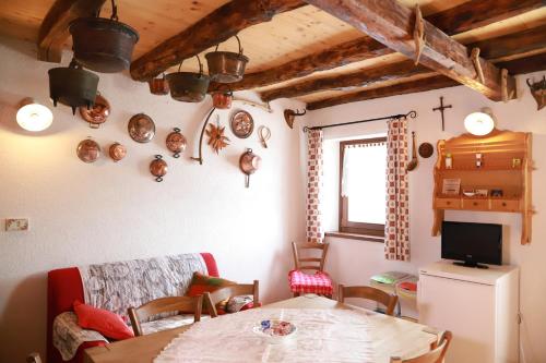 ein Wohnzimmer mit einem Tisch und einem TV sowie einem Tisch und Stühlen in der Unterkunft La casa del Ghiro - PARCO DOLOMITI BELLUNESI in Corazzai