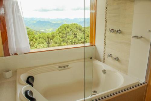 a bathroom with a bath tub and a window at Hospedaria Aikó in São Bento do Sapucaí