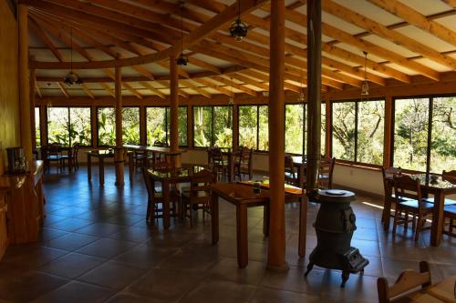 a restaurant with wooden tables and chairs and windows at El Toucanet Lodge in El Copey