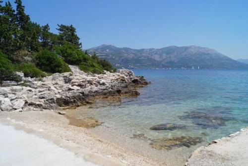 a beach with rocks and the blue water at Apartment Stanisic in Korčula