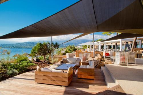 an outdoor patio with a table and chairs under a large umbrella at La Plage Casadelmar in Porto-Vecchio