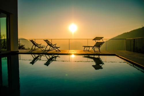 a pool with chairs and the sunset in the background at Il Bagnolo Eco Lodge in Salò