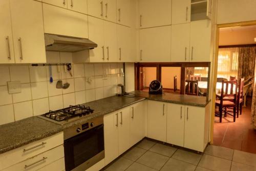 a kitchen with white cabinets and a stove top oven at Casa Caramba in Praia do Tofo