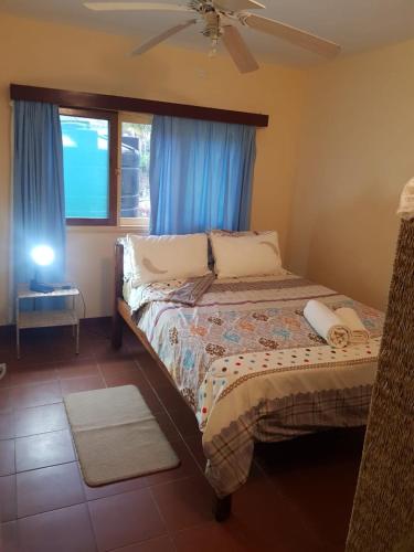 a bedroom with a bed and a window with blue curtains at Casa Caramba in Praia do Tofo