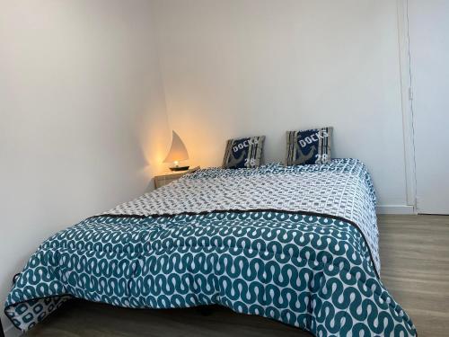 une chambre avec un lit avec une couette bleue et blanche dans l'établissement L’Escapade Normande, au Tréport