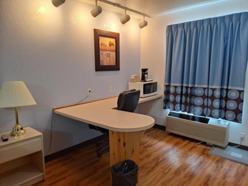 an office with a desk and a table with a chair at Super 8 by Wyndham Three Hills AB in Three Hills