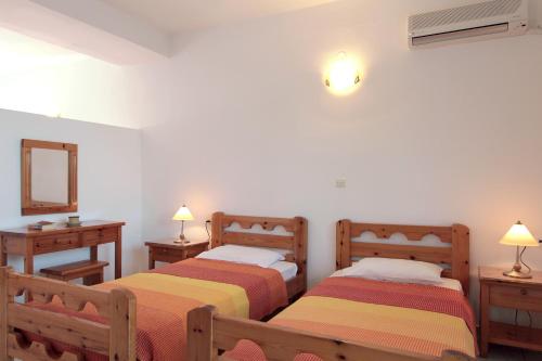 two beds in a room with two lamps and a mirror at Apollon Apartments in Akrogiali
