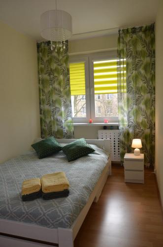 a bedroom with a bed and two windows at Apartament Modlin in Nowy Dwór Mazowiecki