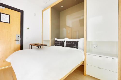 1 dormitorio con 1 cama blanca grande y espejo en Sonder The Beverley en Toronto