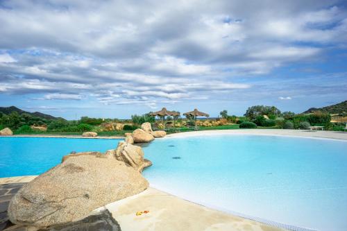 a large swimming pool with blue water and rocks at BGItalianVacation - Ville Li Conchi in Castiadas