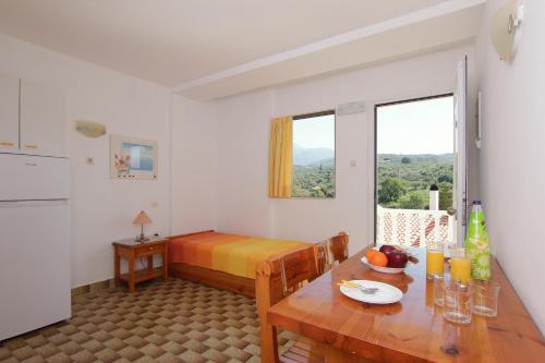AkrogialiにあるApollon Apartmentsのテーブル、ベッド、テーブル、椅子が備わる小さな客室です。