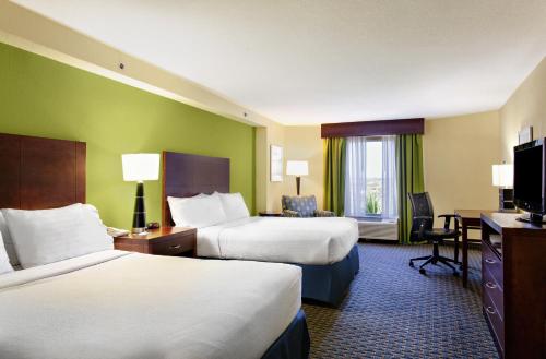 a hotel room with two beds and a desk at Holiday Inn Hotel & Suites Daytona Beach On The Ocean, an IHG Hotel in Daytona Beach