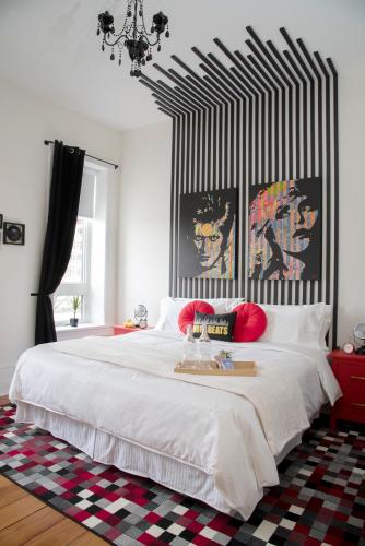 a bedroom with a large white bed with red pillows at The Juniper Inn in St. Catharines