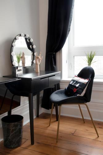 a black desk with a chair and a mirror at The Juniper Inn in St. Catharines