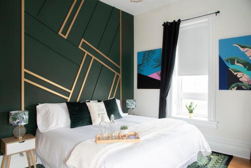 a bedroom with a white bed with a green wall at The Juniper Inn in St. Catharines