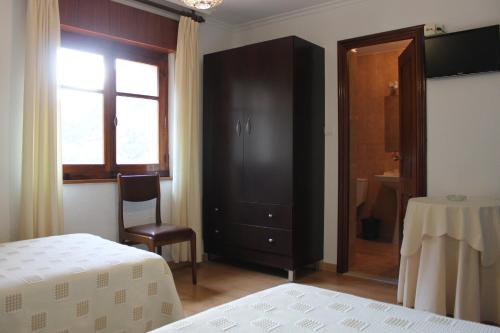 a bedroom with a black cabinet and a table and a window at Hostal Monte Rio in Peñamellera Alta