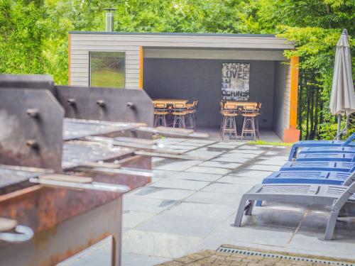 a patio with chairs and tables and an umbrella at Lavish Holiday Home in Durbuy with Garden in Durbuy