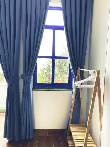 a window with blue curtains in a room at Cát Homestay in Quy Nhon
