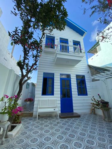 a white house with blue windows and a blue door at Cát Homestay in Quy Nhon