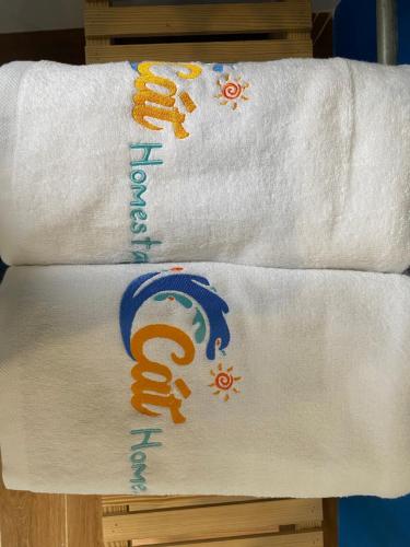 two white towels on a wooden rack with writing on them at Cát Homestay in Quy Nhon