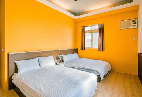two beds in a room with orange walls at Fun Trip - Fu May Sea View Holiday house l 無敵海景交誼廳 l 附汽機車租賃 l in Taitung City