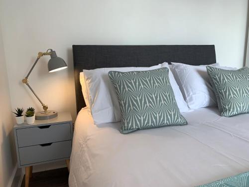 a bed with white pillows and a lamp on a night stand at Basingstoke Spectacular 1 Bedroom Apartment in Basingstoke