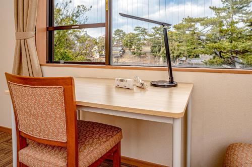 escritorio con lámpara, silla y ventana en NARA Visitor Center and Inn, en Nara