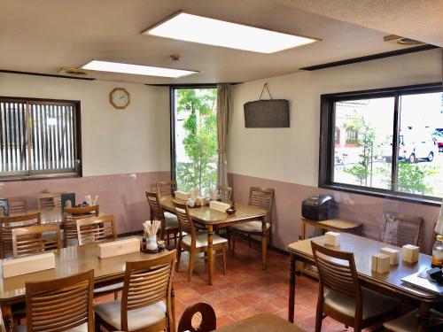 a dining room with tables and chairs and windows at Umeoka Ryokan in Nagano