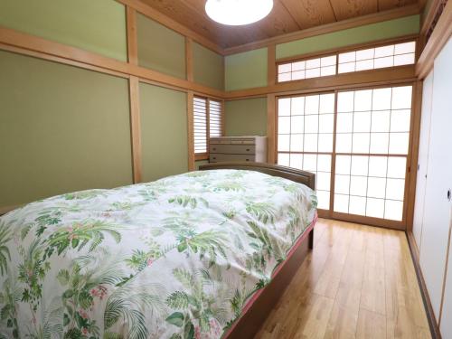 ein Schlafzimmer mit einem Bett in einem Zimmer mit Fenstern in der Unterkunft Friendly Guest House Kawakin in Minamiboso