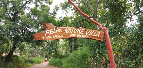 a wooden sign in the middle of a dirt road at Relax Nature Villa in Sigiriya