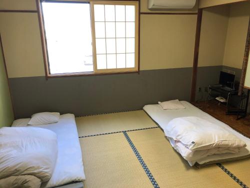 two beds in a room with two windows at Umeoka Ryokan in Nagano