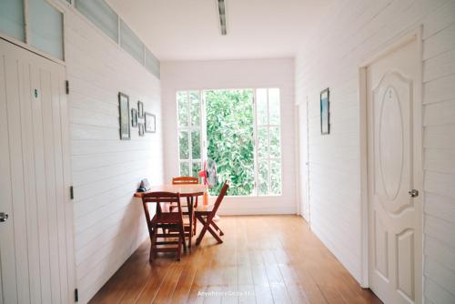 a dining room with a table and chairs and a door at Thirty Tree Garden House in Chumphon