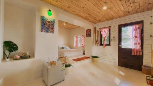 a room with a bed and a refrigerator in it at Maliblues Bed & Art Gallery in Chumphon