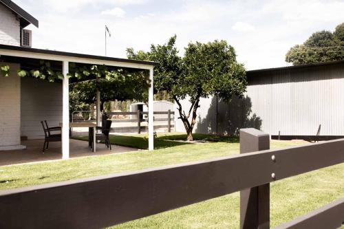 a white fence next to a yard with a table at The Glen Farmhouse on Ovens River in Wangaratta