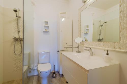 a white bathroom with a toilet and a sink at Casa Beatriz in Carvoeiro