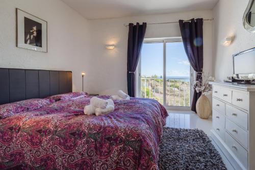a teddy bear laying on a bed in a bedroom at Casa Beatriz in Carvoeiro