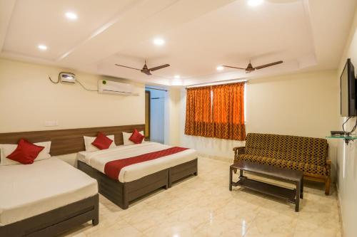 a hotel room with two beds and a chair at Hotel Siri Grand in Visakhapatnam