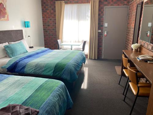 a hotel room with two beds and a desk at Zero Inn Motel in Nhill