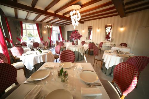 サン・ティレール・デュ・アルクエにあるHotel Restaurant Le Lion d'Orのダイニングルーム(白いテーブル、赤い椅子付)