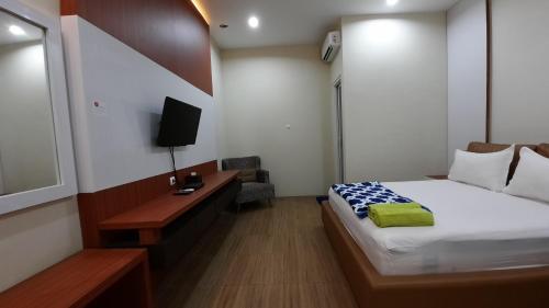 a bedroom with a bed and a desk with a television at The Peak Guest House in Jember