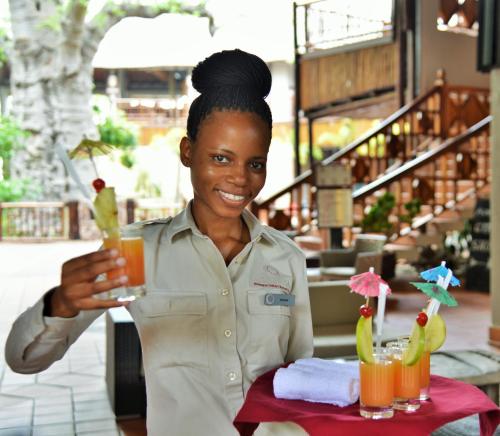 a woman holding a drink in a restaurant at Cresta Mowana Safari Resort & Spa in Kasane