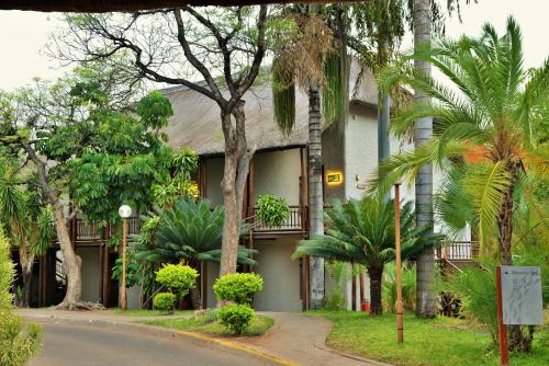 a building with palm trees in front of a street at Cresta Mowana Safari Resort & Spa in Kasane