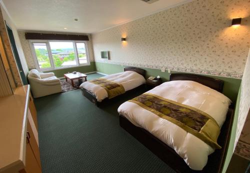 a hotel room with two beds and a window at Auberge Mermaid in Fujikawaguchiko