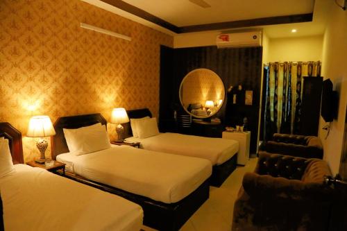 um quarto de hotel com duas camas e uma cadeira em Fiesta Inn Hotel & Resorts Multan em Multan
