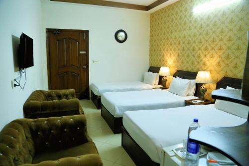 a hotel room with two beds and a tv at Fiesta Inn Hotel & Resorts Multan in Multan