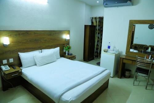 a bedroom with a bed and a desk and a mirror at Fiesta Inn Hotel & Resorts Multan in Multan
