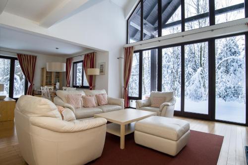 a living room with white furniture and large windows at Hotel SPA Dr Irena Eris Wzgórza Dylewskie - Siedliska in Wysoka Wieś